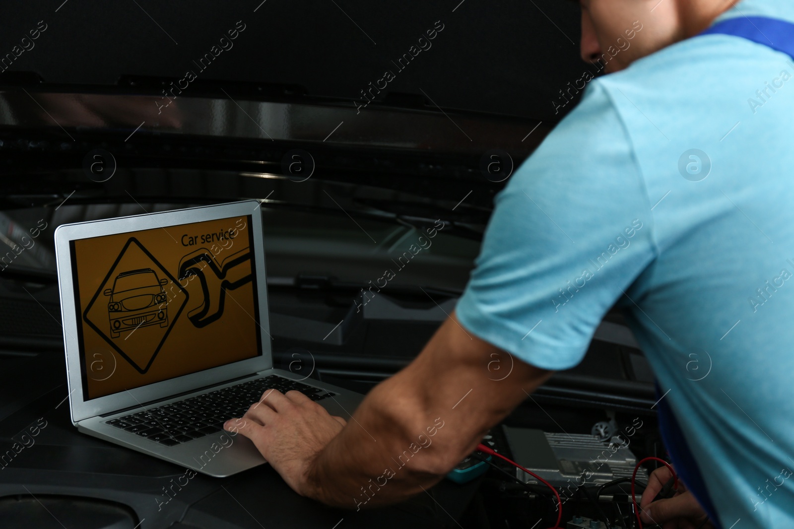 Photo of Mechanic with laptop doing car diagnostic at automobile repair shop, closeup