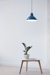 Photo of Modern lamp with plant on table indoors