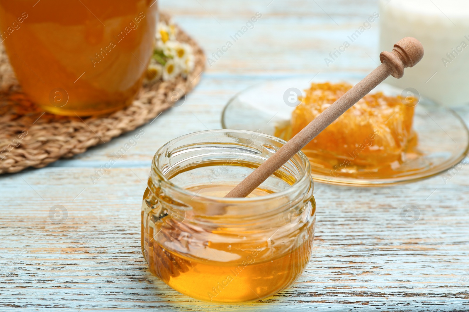 Photo of Tasty honey on light blue wooden table, closeup