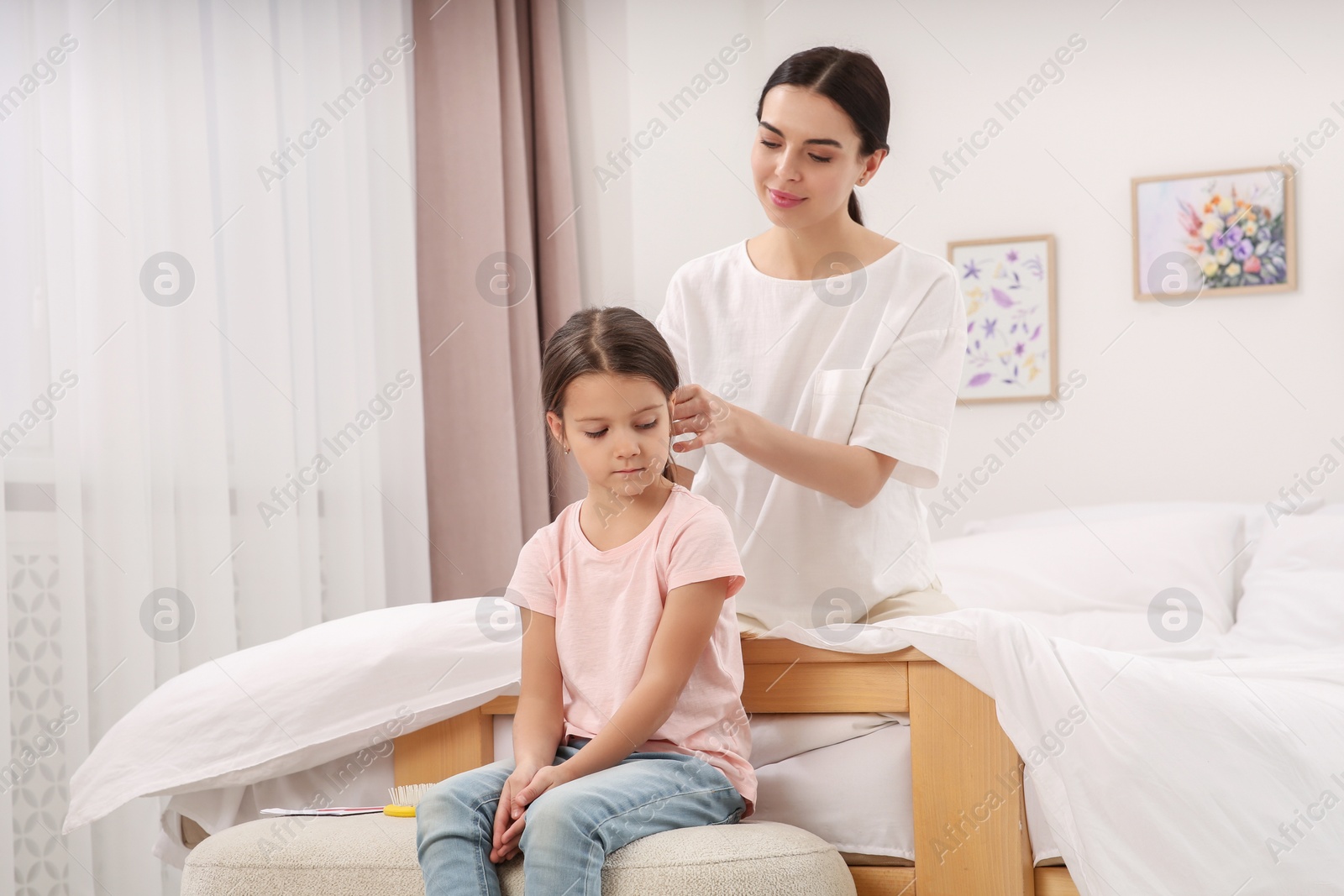 Photo of Happy woman and her daughter spending time together on bed at home. Mother's day celebration