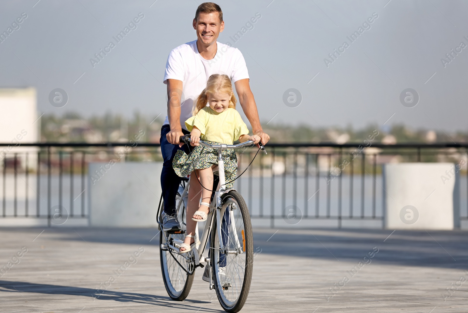 Photo of Father and daughter riding bicycle outdoors on sunny day