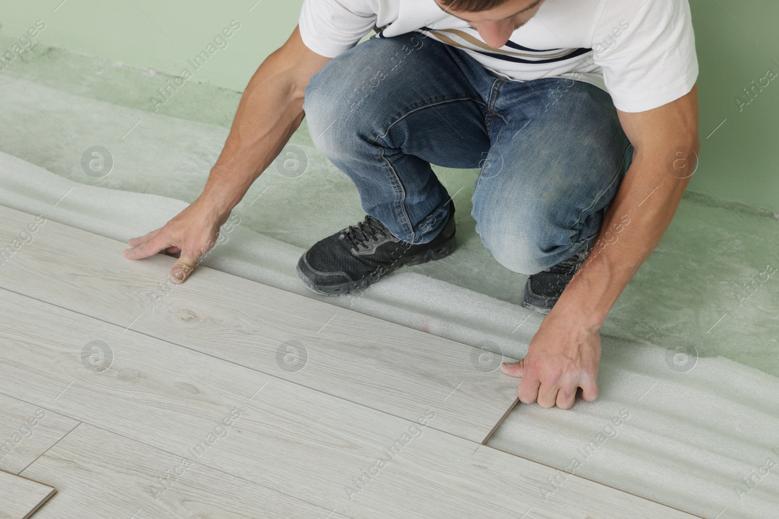 Photo of Man installing new laminate flooring indoors, closeup