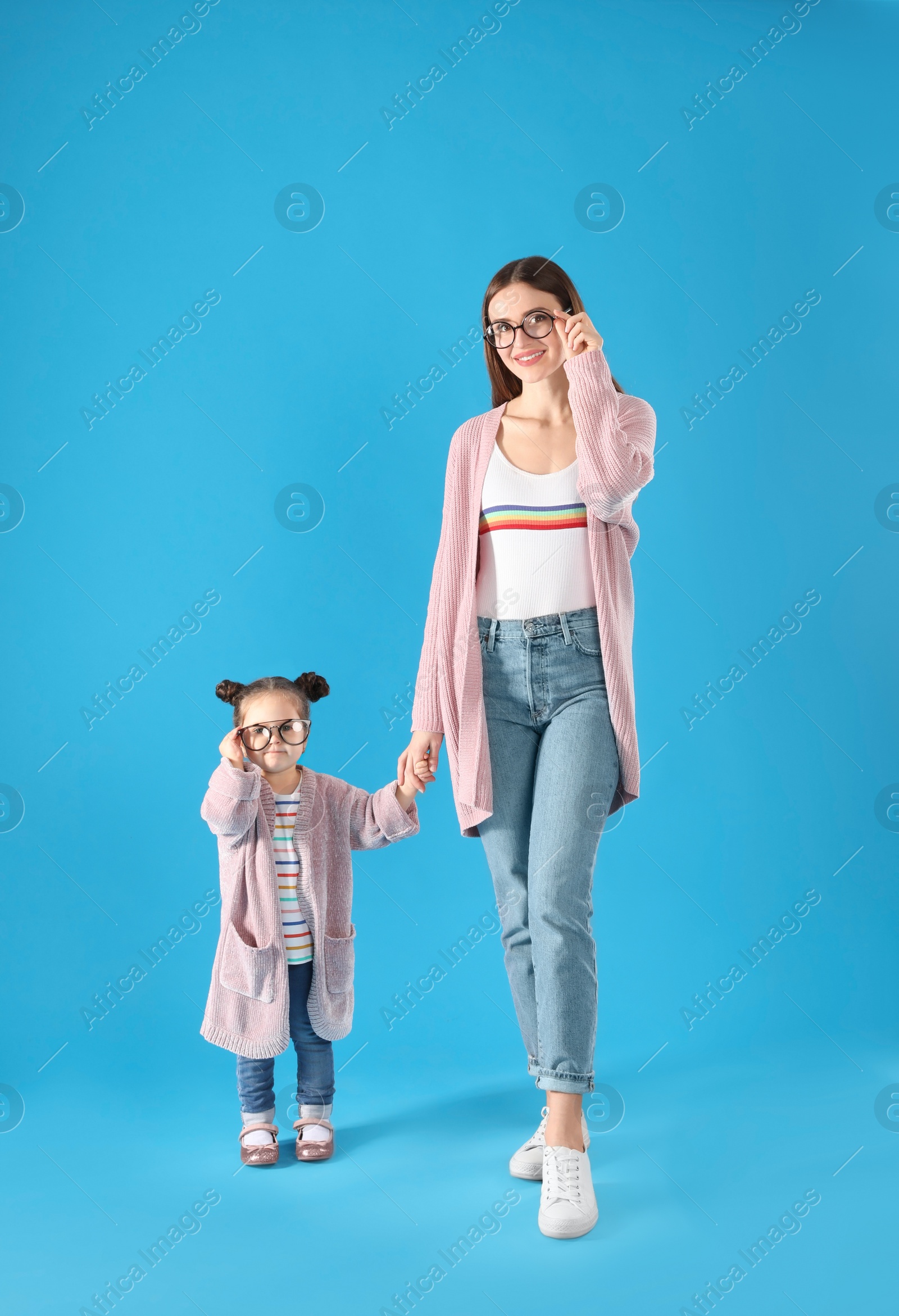 Photo of Young mother and little daughter with glasses on blue background