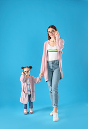 Young mother and little daughter with glasses on blue background