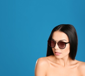 Photo of Beautiful woman wearing sunglasses on blue background. Space for text