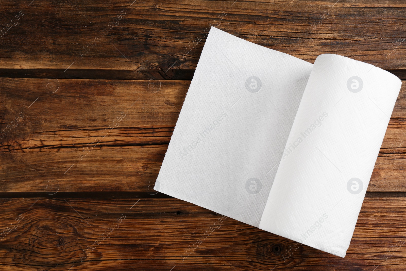 Photo of Roll of paper towels on wooden table, top view. Space for text