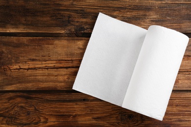 Roll of paper towels on wooden table, top view. Space for text