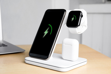Set of gadgets charging with wireless pad on wooden table indoors