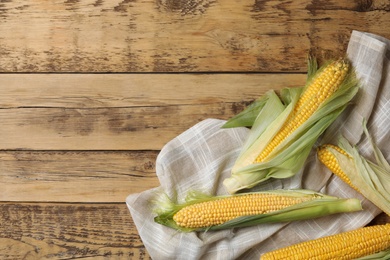 Photo of Corn cobs on wooden table, flat lay. Space for text