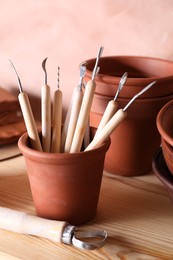 Set of different crafting tools and clay dishes on wooden table in workshop