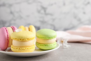 Photo of Delicious colorful macarons on grey table, closeup. Space for text