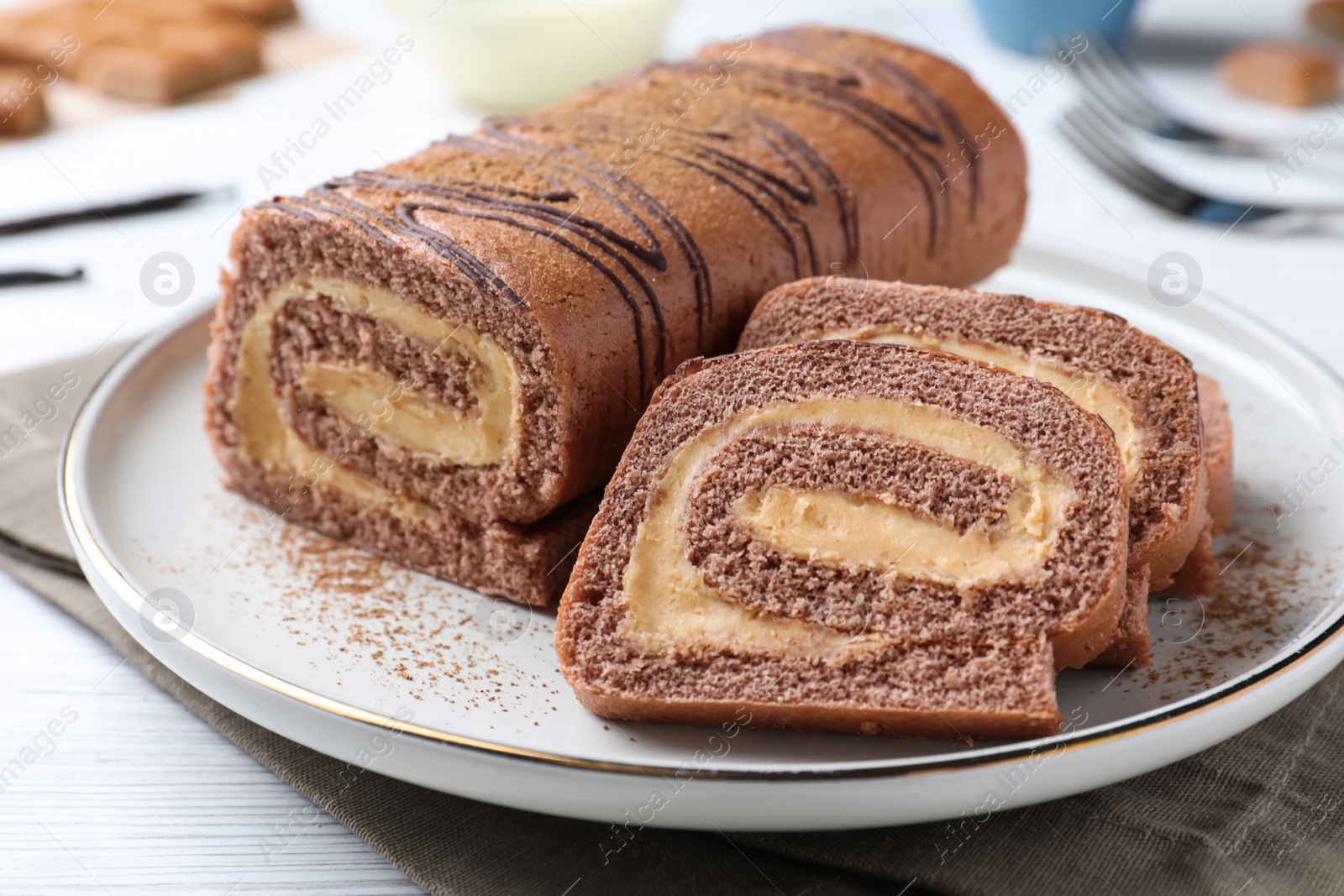 Photo of Tasty chocolate cake roll with cream on white wooden table, closeup