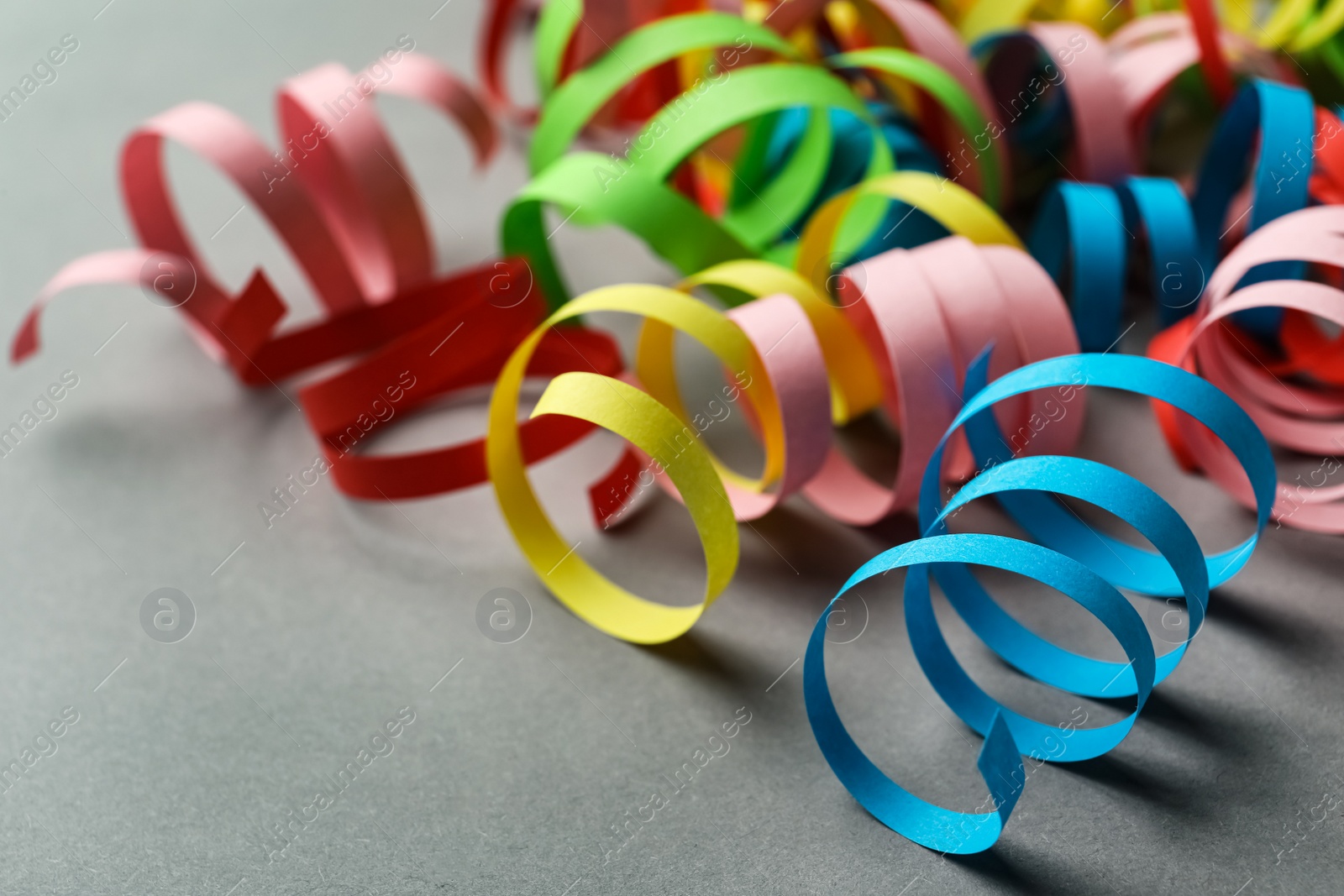 Photo of Colorful serpentine streamers on grey background, closeup