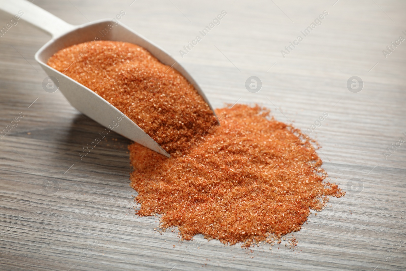 Photo of Pink salt with spices and scoop on wooden table