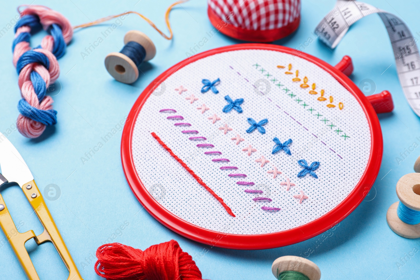 Photo of Embroidery and different sewing accessories on light blue background