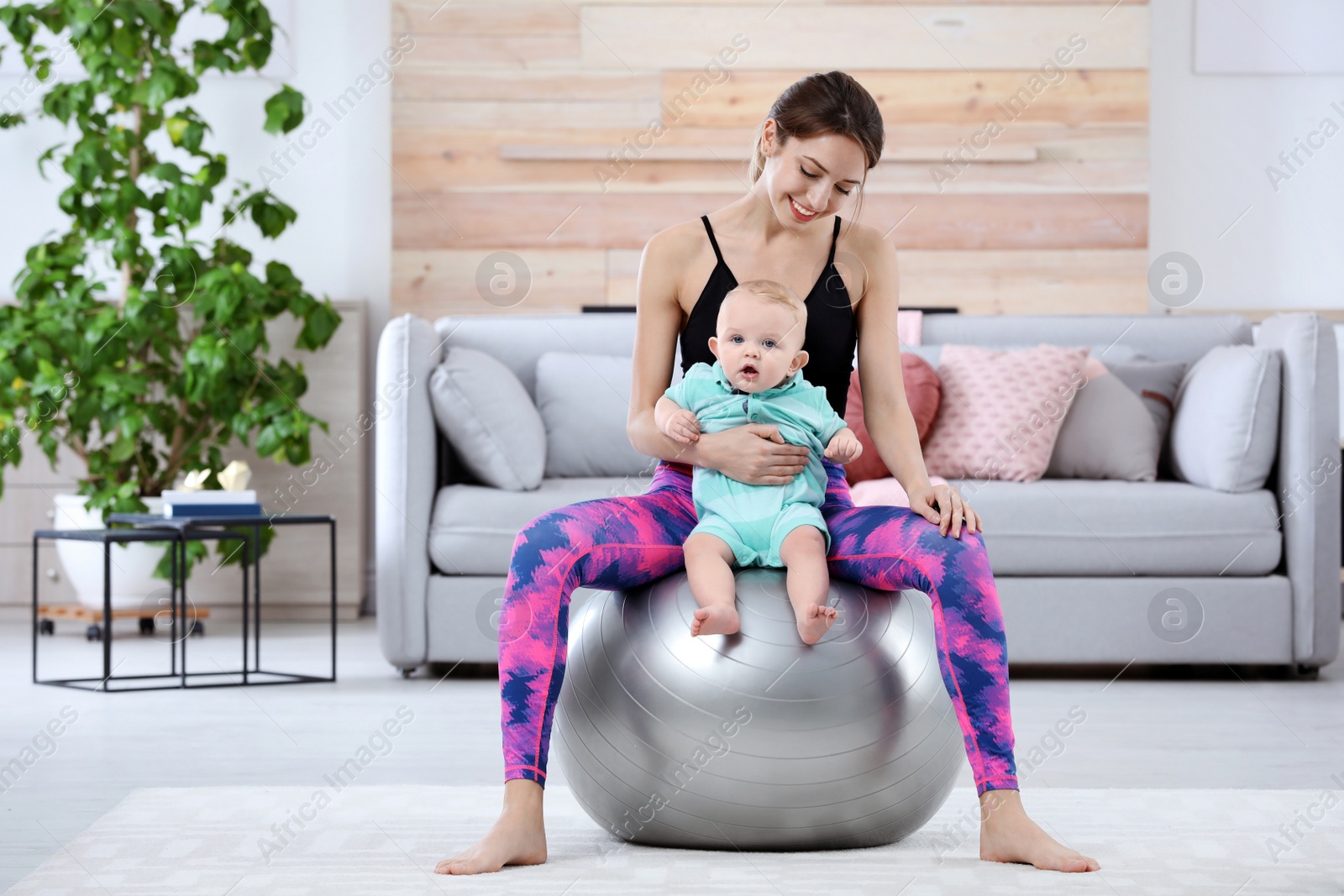 Photo of Young sportive woman doing exercise with her son at home. Fitness training