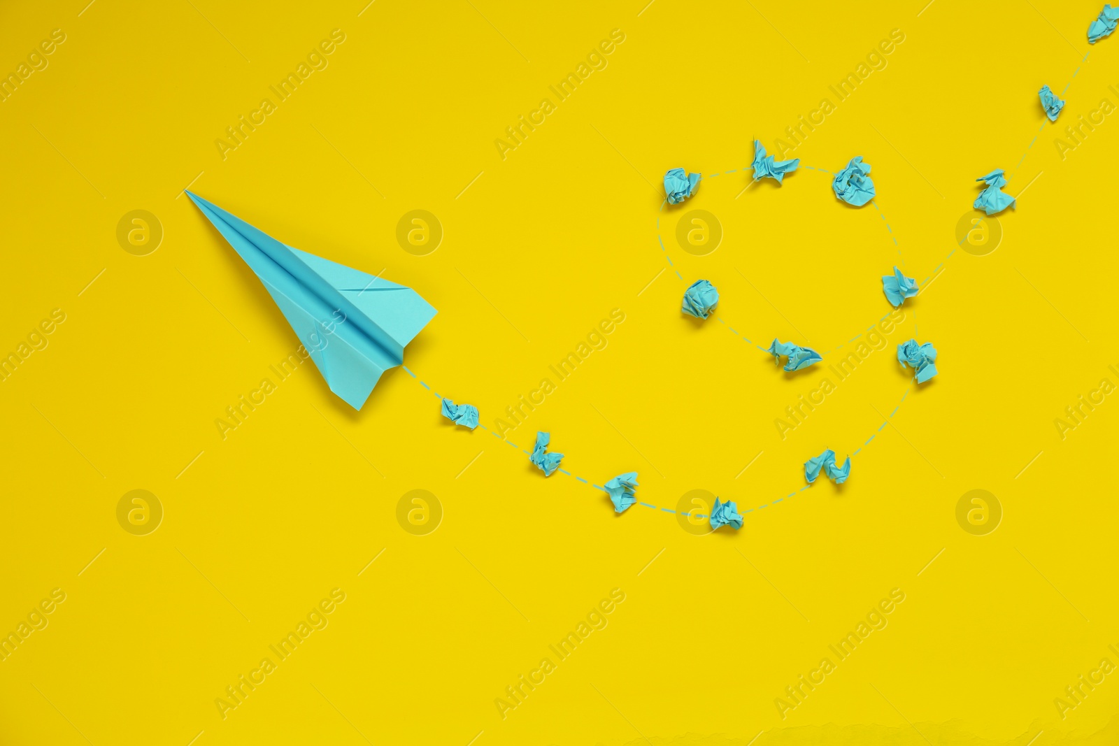 Photo of Handmade plane and many crumpled pieces of paper on yellow background, flat lay