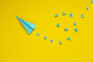 Handmade plane and many crumpled pieces of paper on yellow background, flat lay