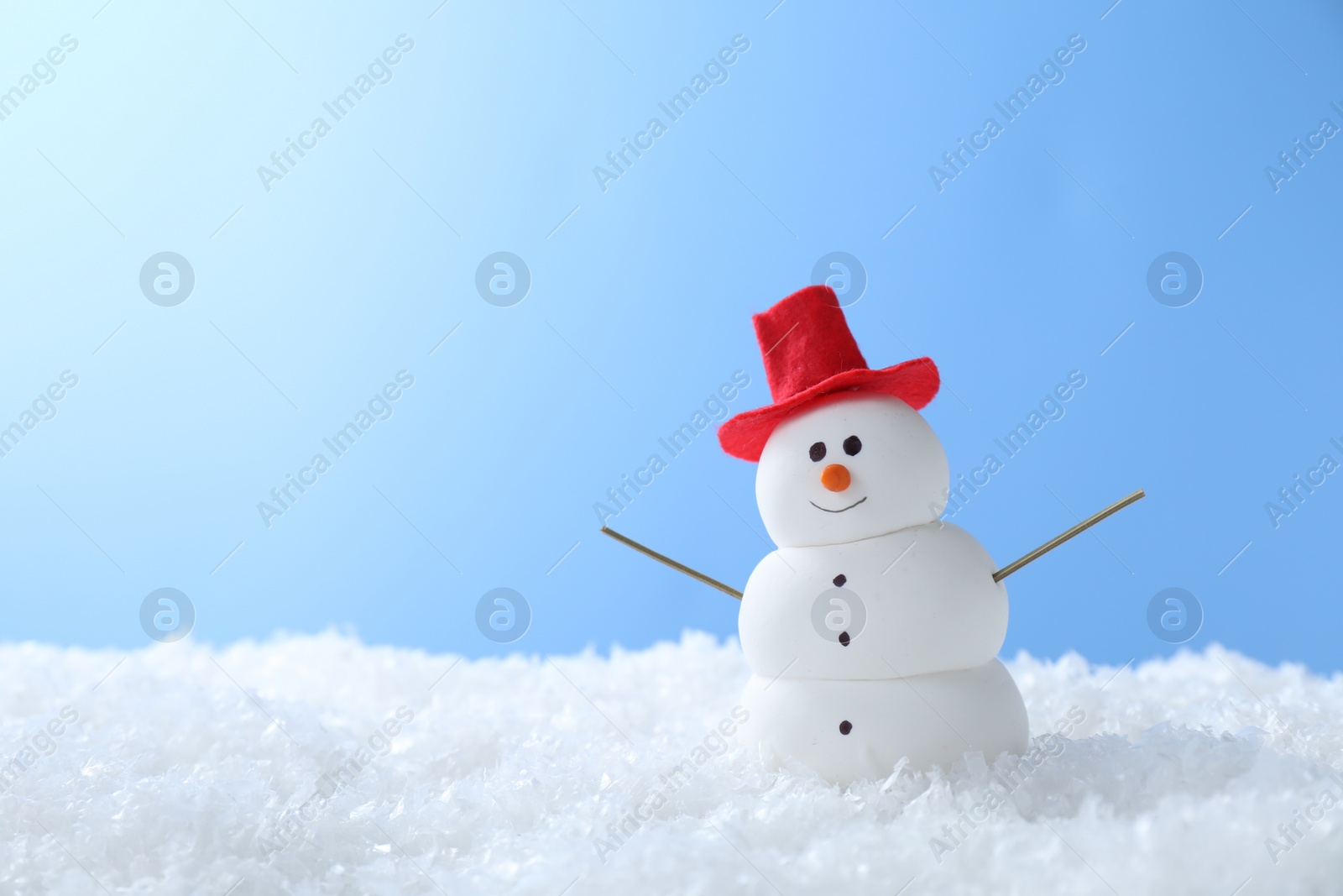 Photo of Funny snowman on snow against light blue background, space for text