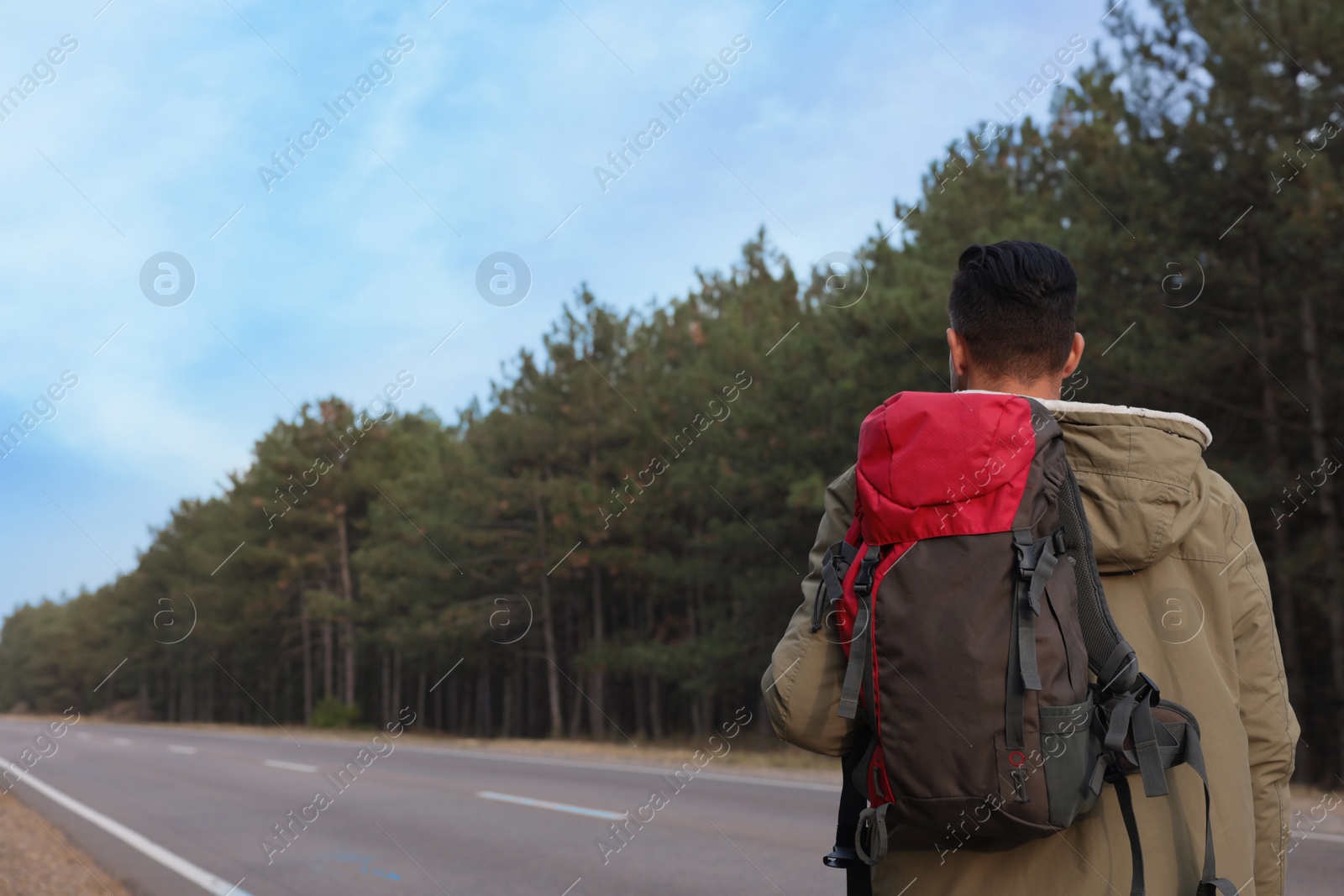 Photo of Man with backpack on road near forest, back view