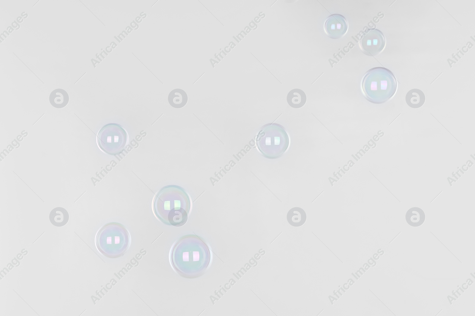 Photo of Beautiful translucent soap bubbles on light background