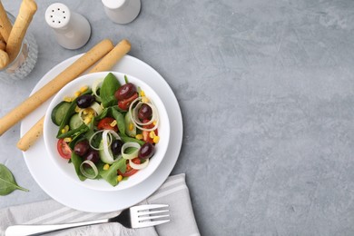 Photo of Tasty salad with leek and olives served with grissini on grey table, flat lay. Space for text