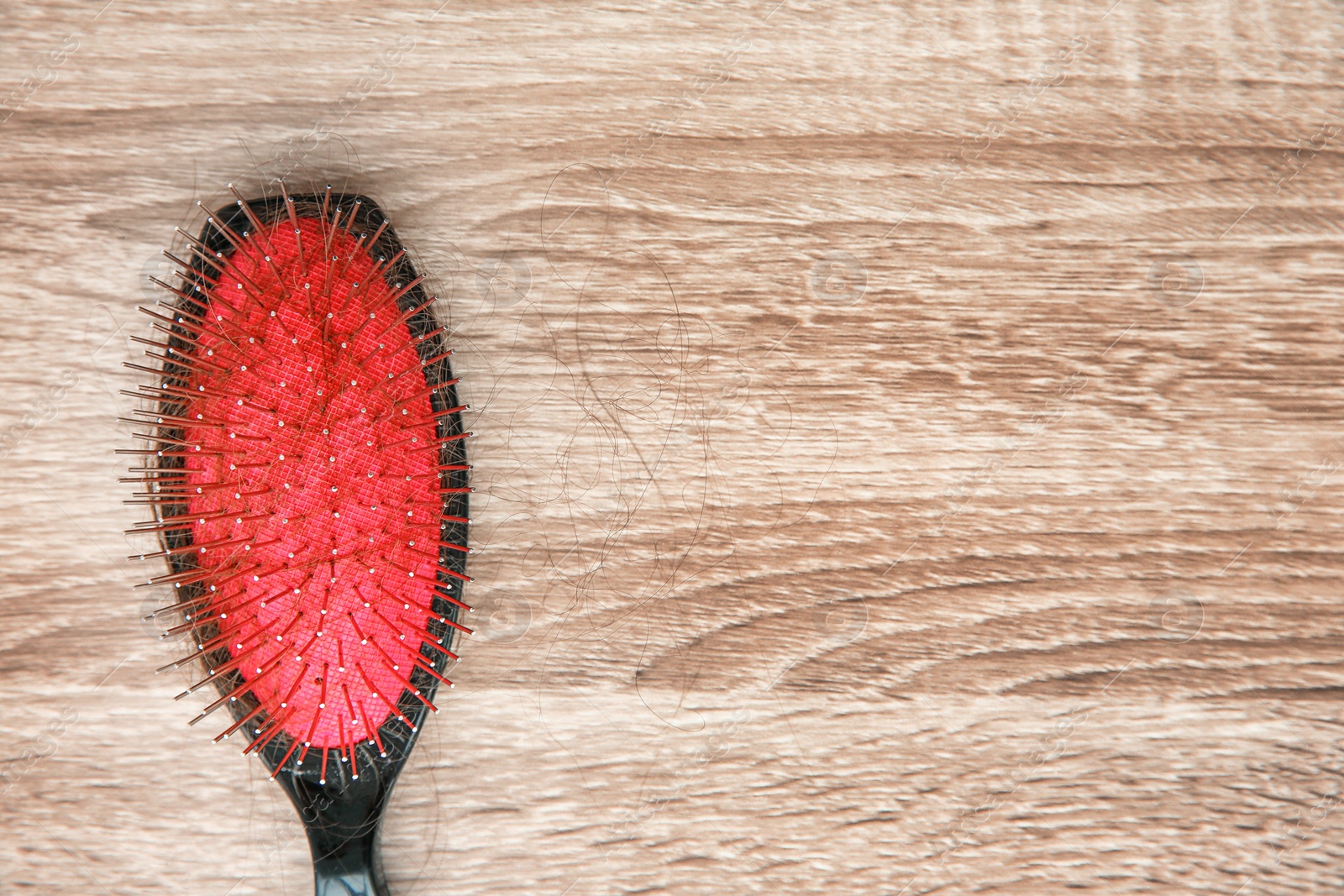 Photo of Brush with lost hair on wooden background. Alopecia problem