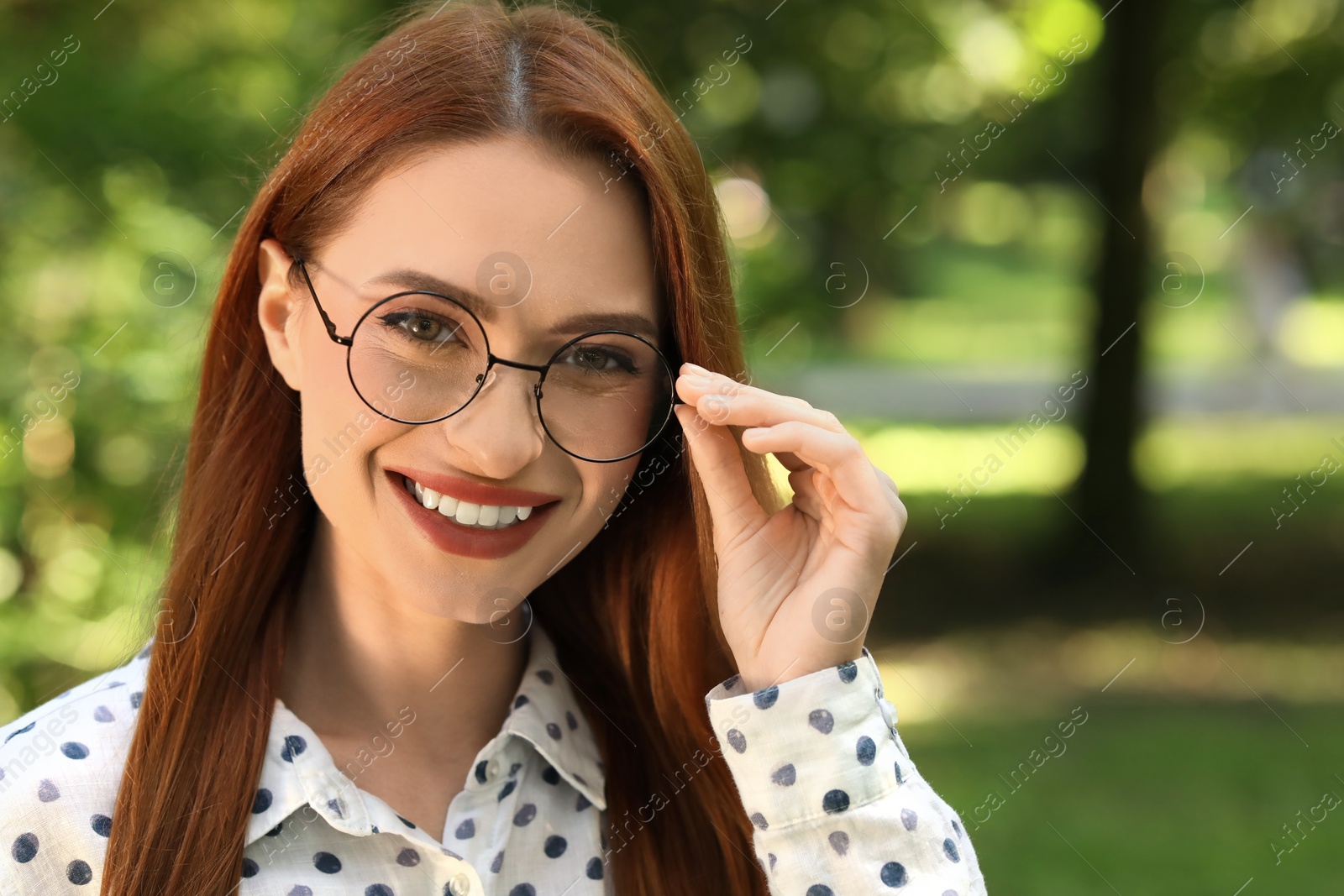 Photo of Portrait of happy young woman with glasses outdoors. Space for text. Lady with beautiful smile looking into camera