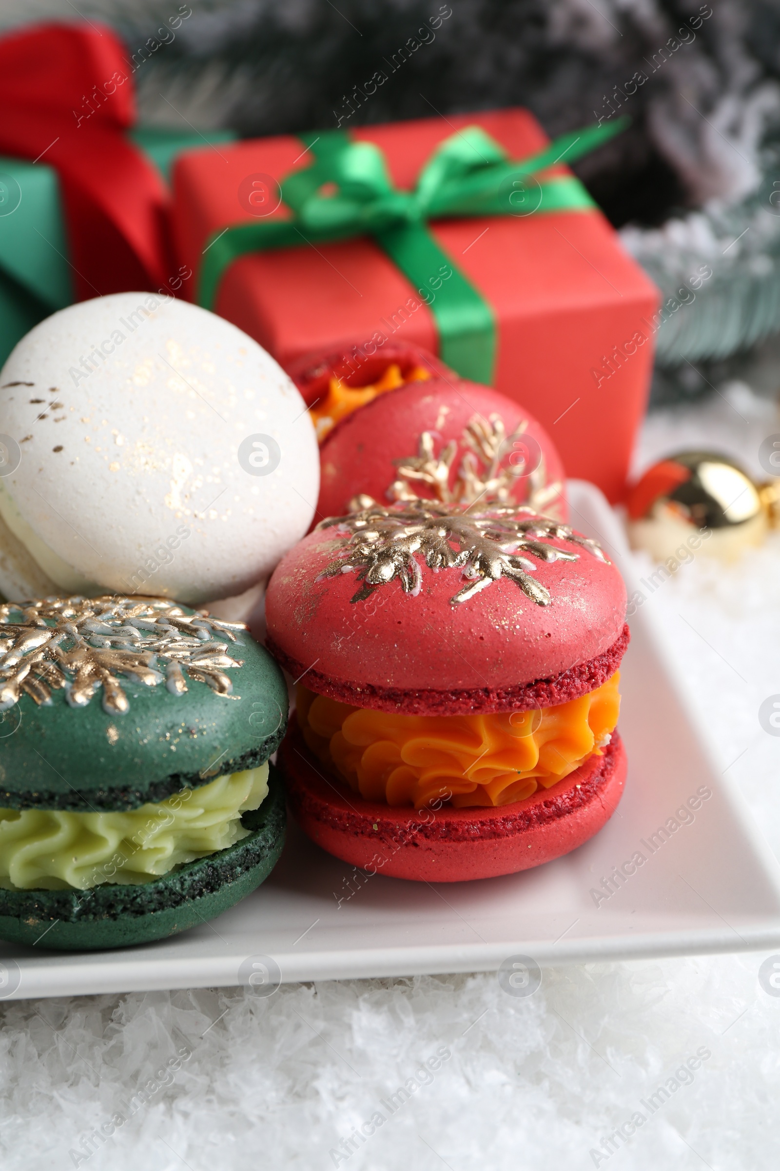 Photo of Beautifully decorated Christmas macarons and festive decor on snow, closeup