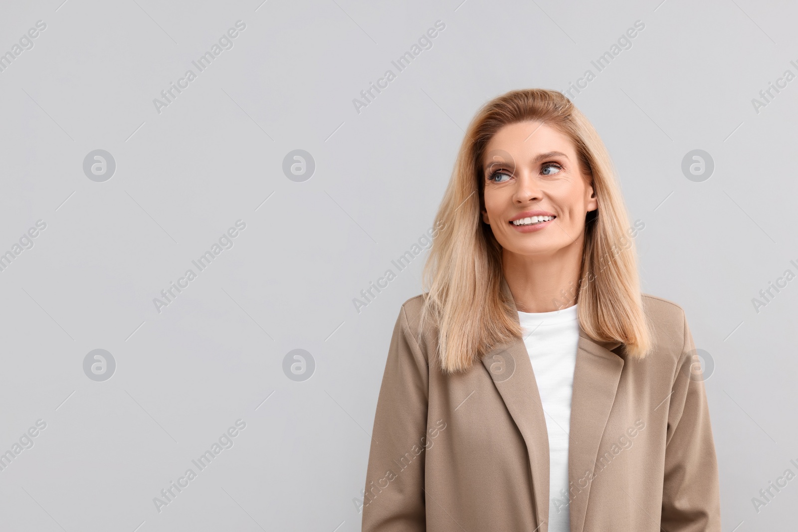 Photo of Portrait of smiling middle aged businesswoman on light grey background. Space for text