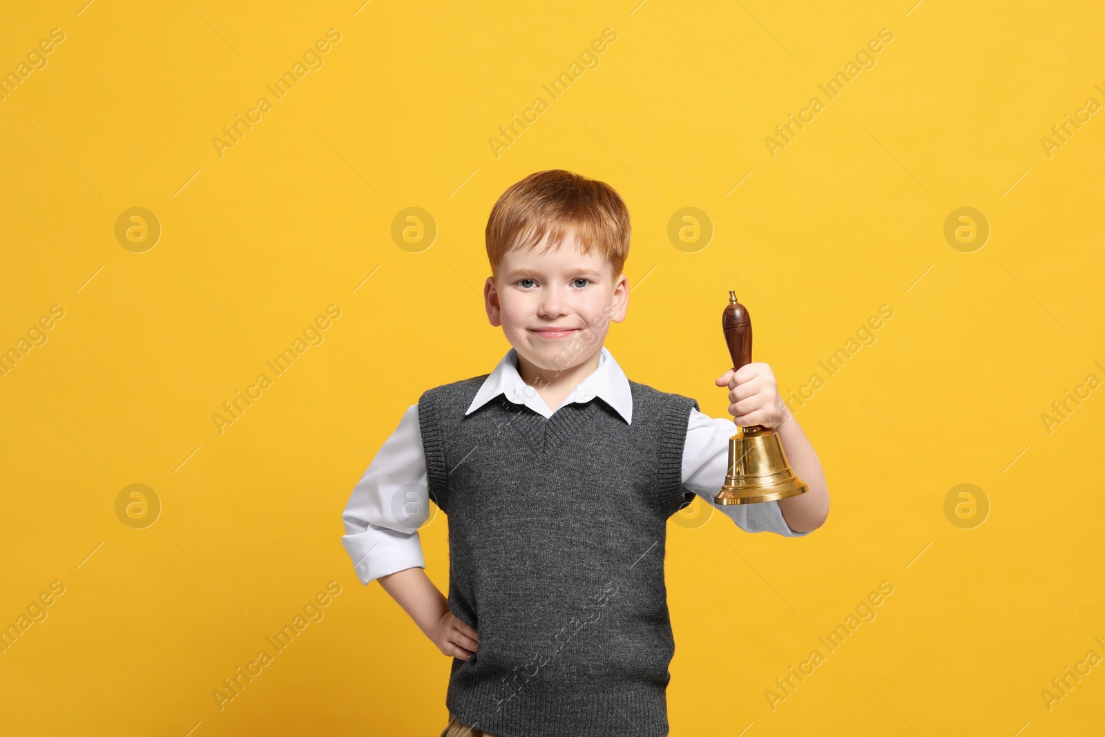 Photo of Pupil with school bell on orange background