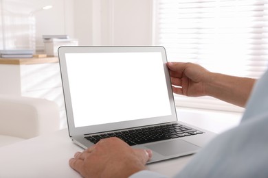 Photo of Man with modern laptop at white table indoors, closeup. Space for design