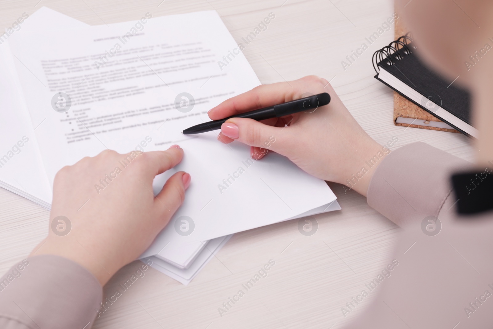 Photo of Woman signing document at wooden table, closeup