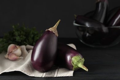 Photo of Ripe purple eggplants on black wooden table, closeup