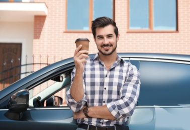 Photo of Attractive young man with cup of coffee near luxury car outdoors