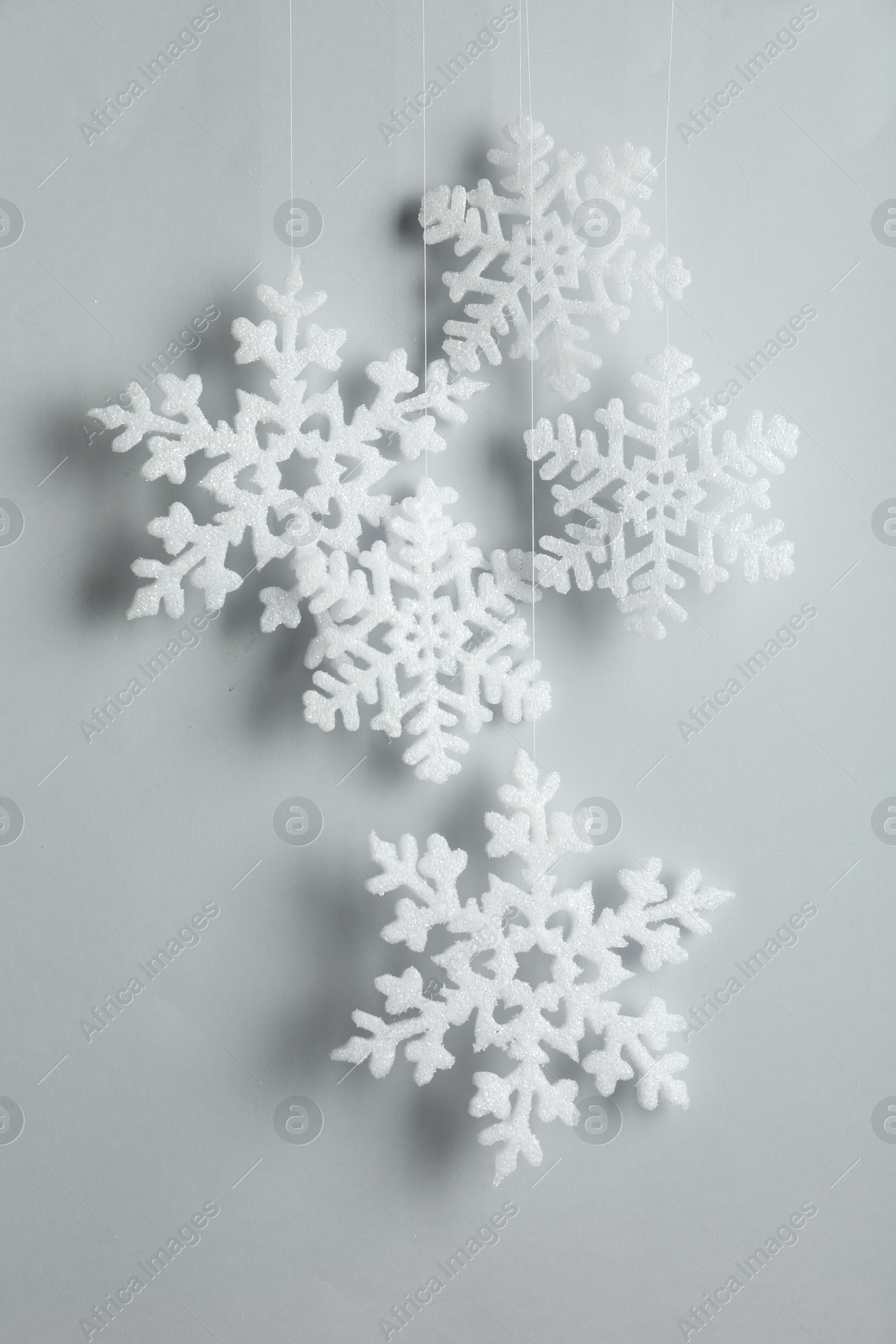 Photo of Beautiful decorative snowflakes hanging on light grey background