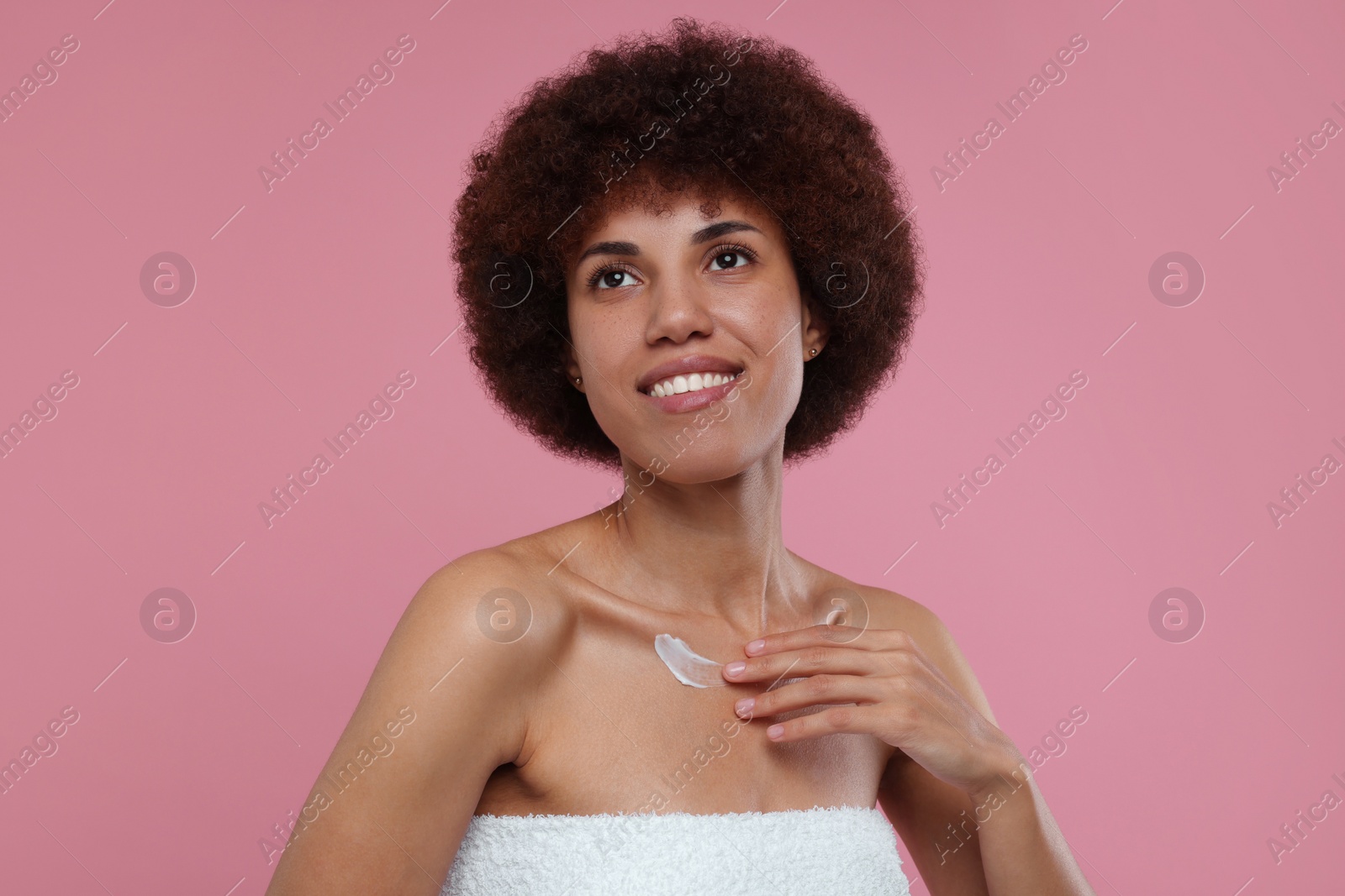 Photo of Beautiful young woman applying cream onto body on pink background