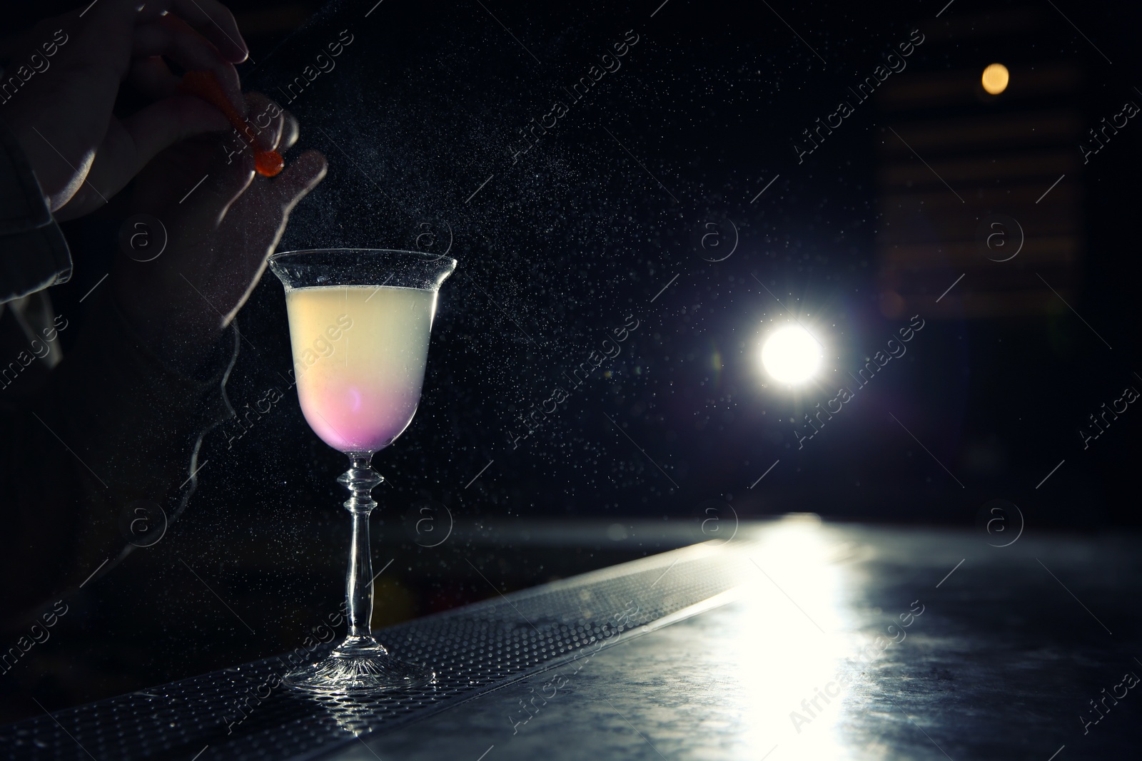 Photo of Barman adding lemon zest into cosmopolitan martini cocktail at counter, closeup. Space for text