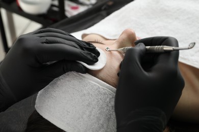 Photo of Cosmetologist using scrubber, closeup. Client having cleansing procedure