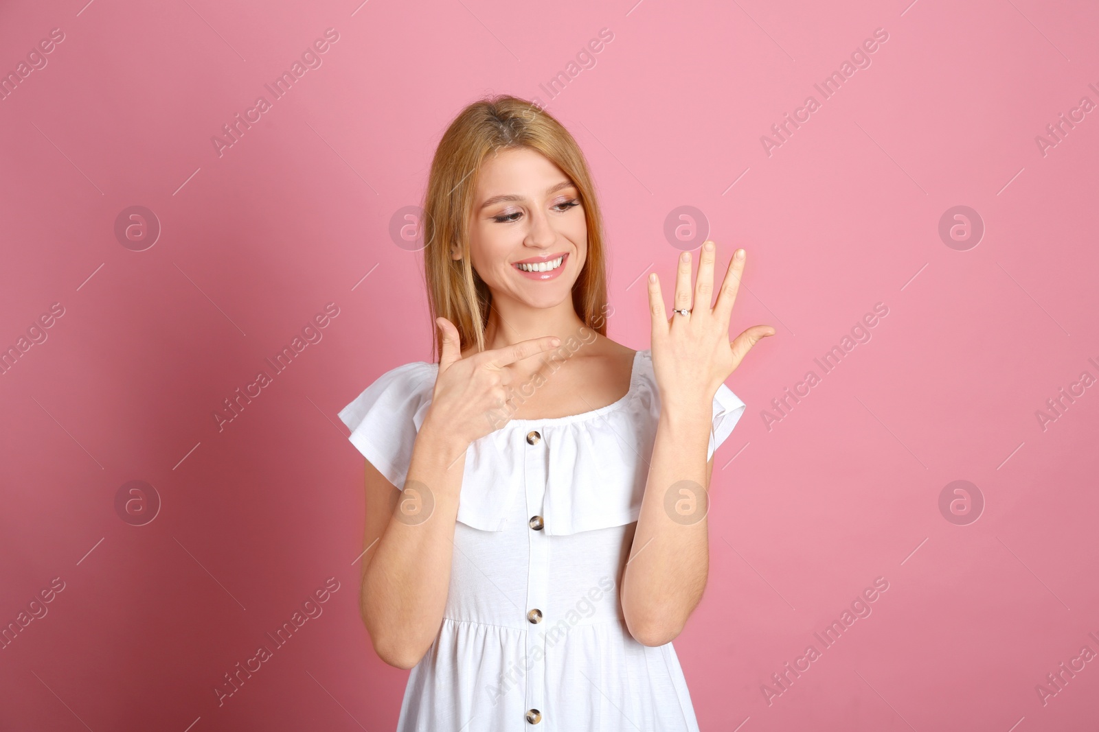 Photo of Happy woman with engagement ring on pink background