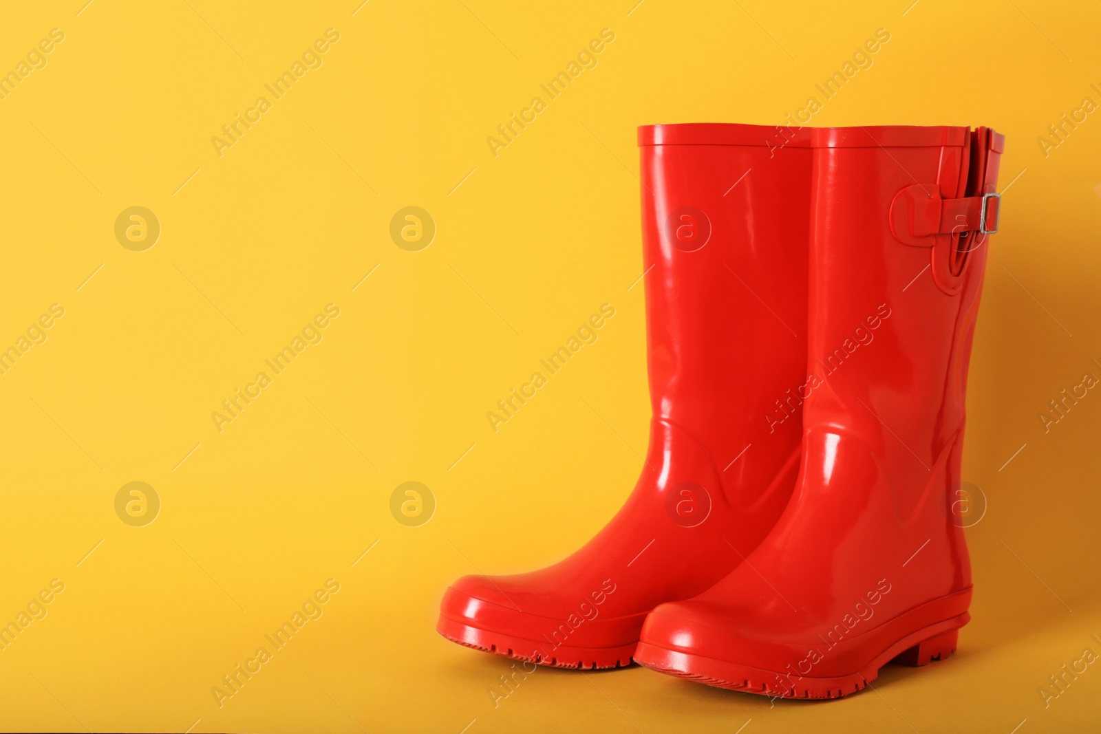 Photo of Pair of red rubber boots on orange background. Space for text
