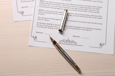 Marriage contracts and pen on light wooden table, top view