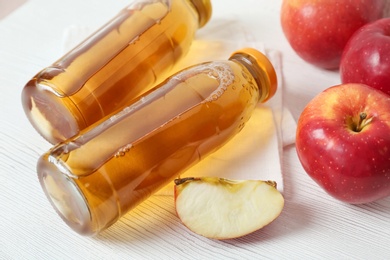 Bottles of apple juice on white table, closeup