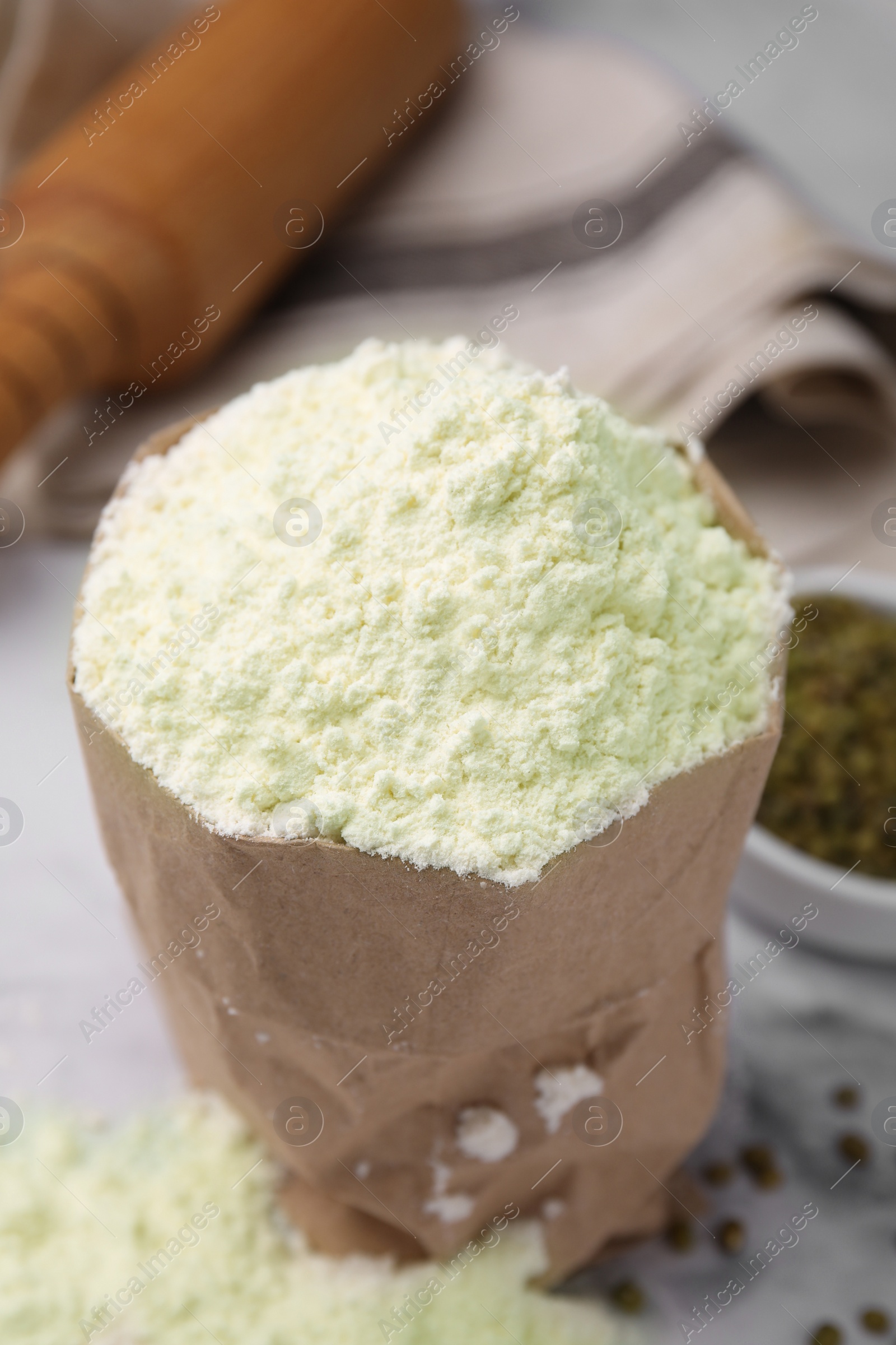 Photo of Mung bean flour in paper bag and seeds on white marble table, closeup