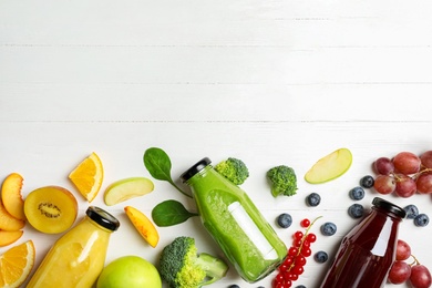 Bottles of delicious juices and fresh fruits on white wooden table, flat lay. Space for text