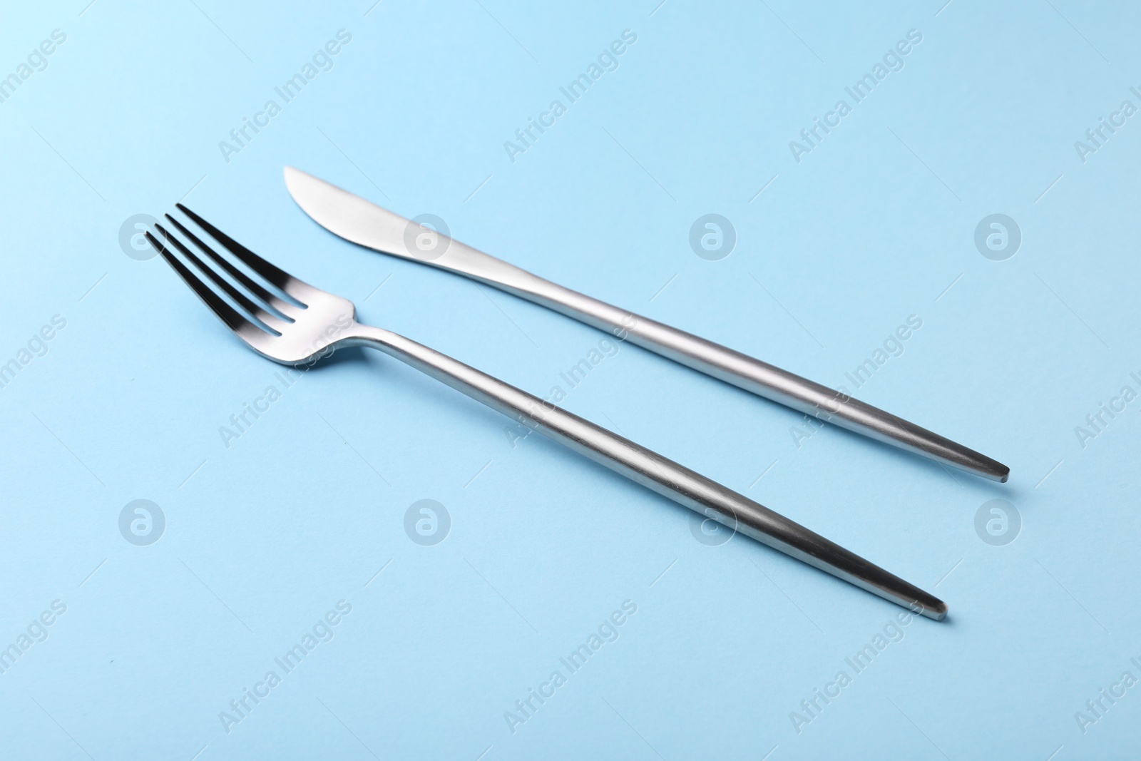 Photo of Stylish cutlery on light blue table, closeup