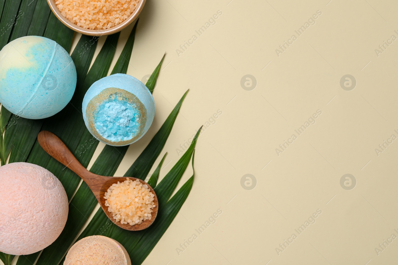 Photo of Bath bombs, green leaf and sea salt on beige background, flat lay. Space for text