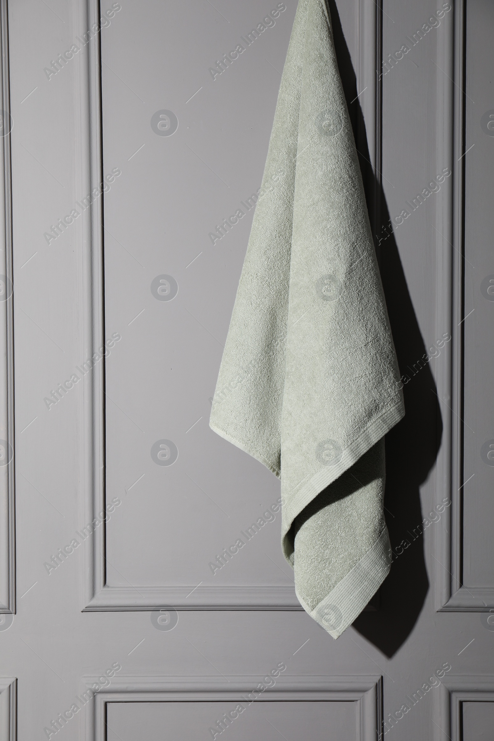 Photo of Soft towel hanging on grey wall indoors, space for text