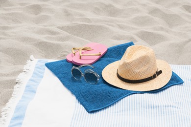 Blanket with blue towel and beach accessories on sand