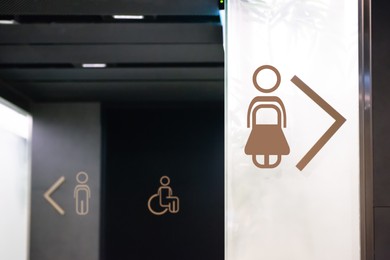 Image of Different public toilet signs with arrows showing directions indoors